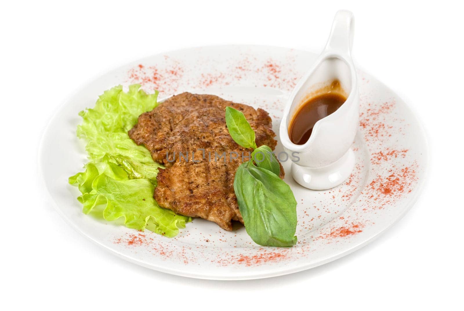 roasted pork steak at the white plate, with greens and sauce