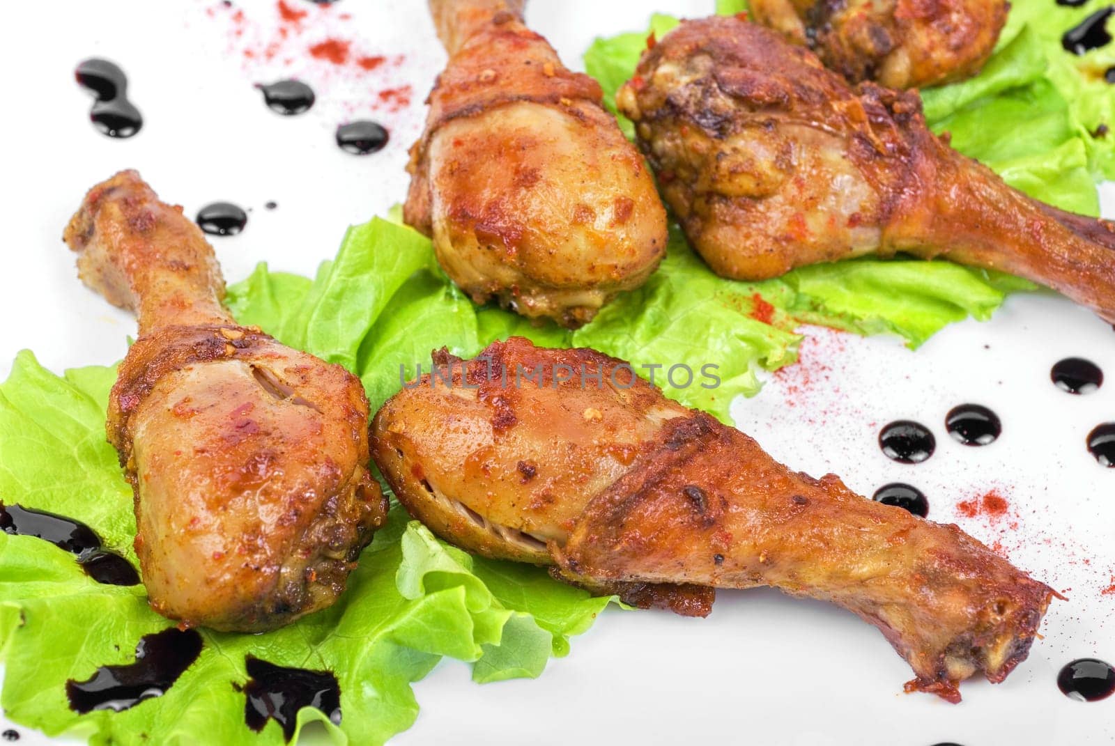 chicken drumstick closeup at white plate with lettuce