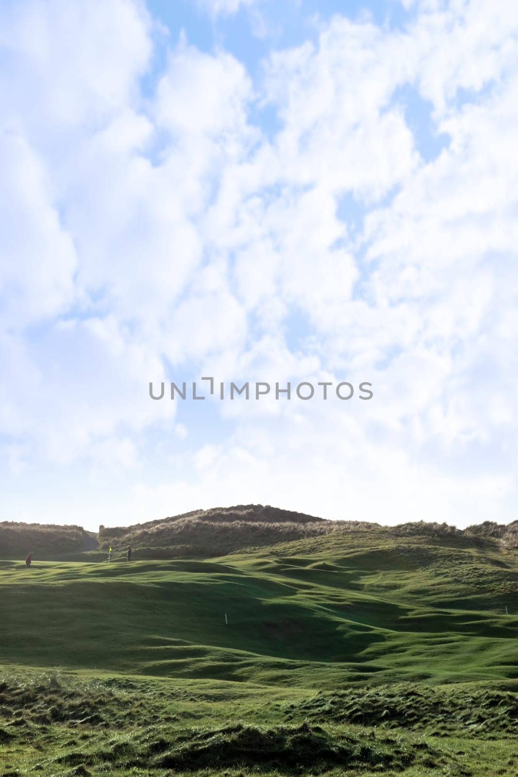 players and a flag waving on a hole on a links golf course in ireland