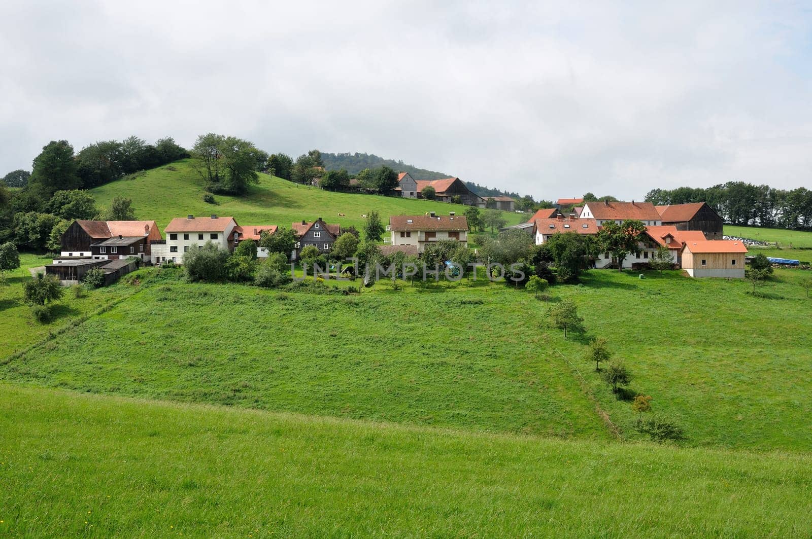 green landscape with a country village over hilly fields, germany