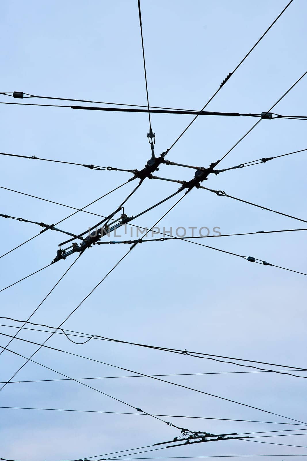 Image of Connecting wires for clean city transportation upward abstract view with overcast blue sky