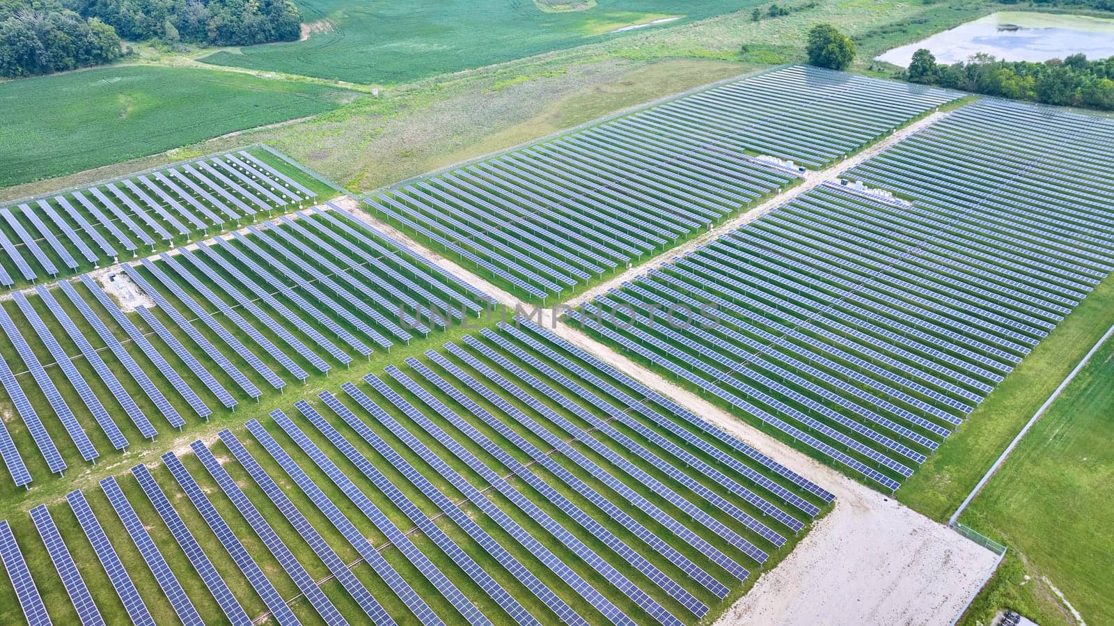 Image of Aerial over solar farm Solar panels facing straight up with swamp and farmland around it