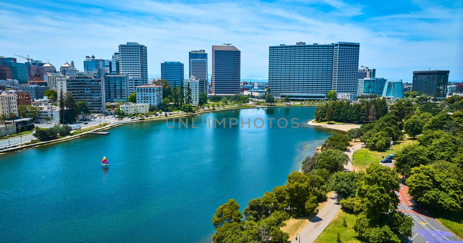 Image of Lone sailboat on Lake Merritt with aerial of downtown Oakland buildings in California