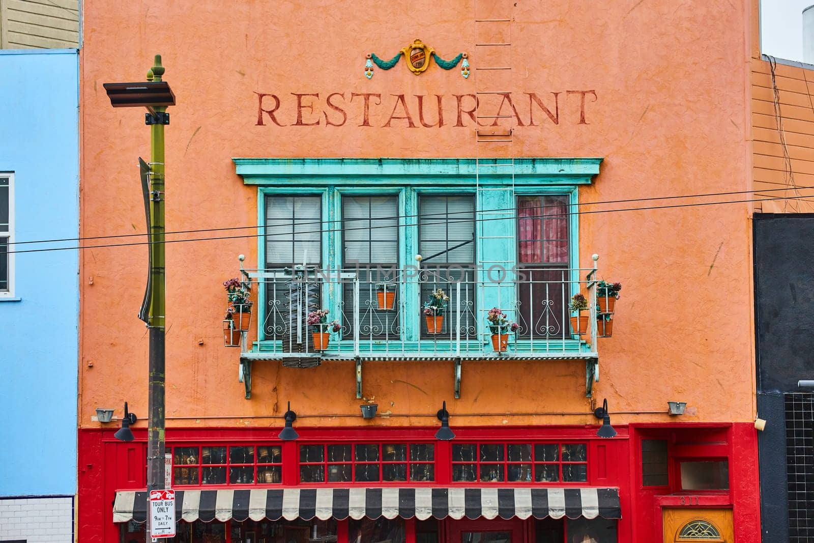 Image of Restaurant building with red paint on bottom and orange on top with teal bay windows