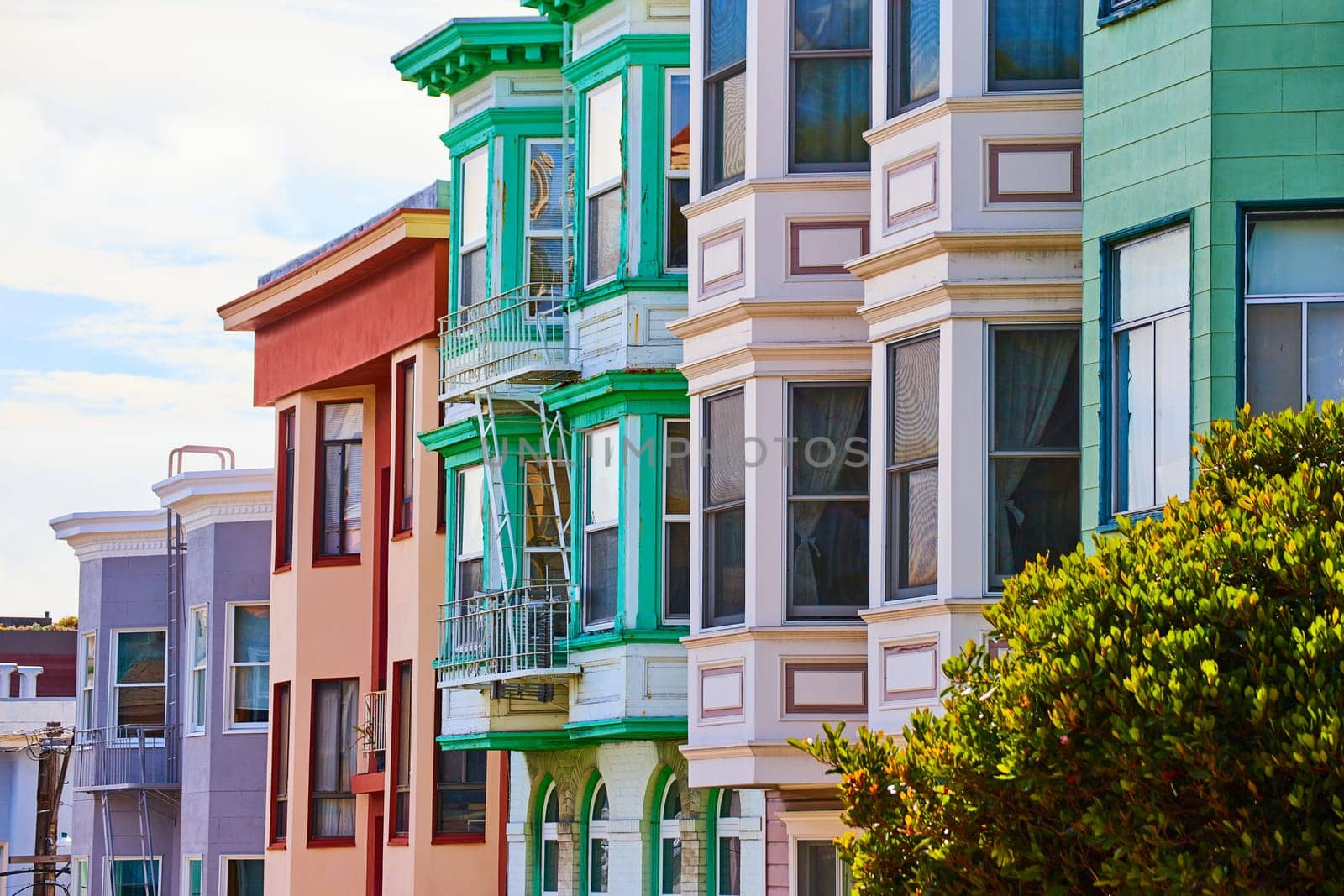 Image of Pastel colored apartment buildings with wide array of bay windows side view