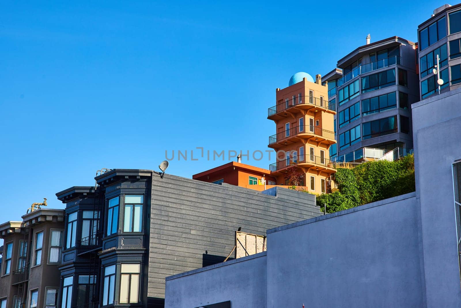 Image of Black apartment building with unique yellow tower structure on hillside behind it