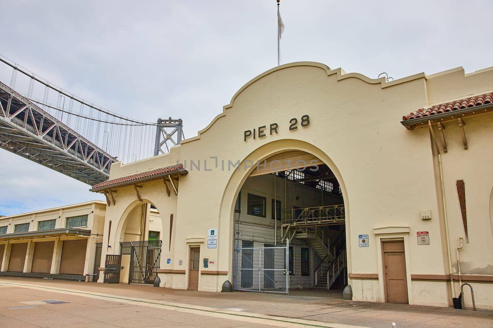 Image of Pier 28 arch entrance to building with staircase inside and Oakland Bay Bridge overhead