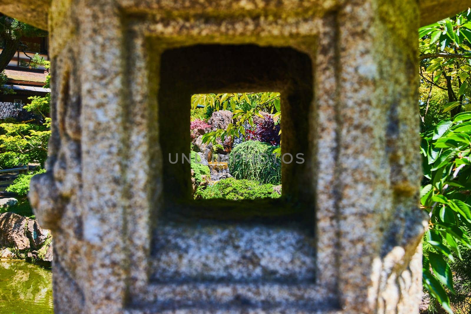 Image of View of garden with mini waterfall seen through Japanese stone lantern