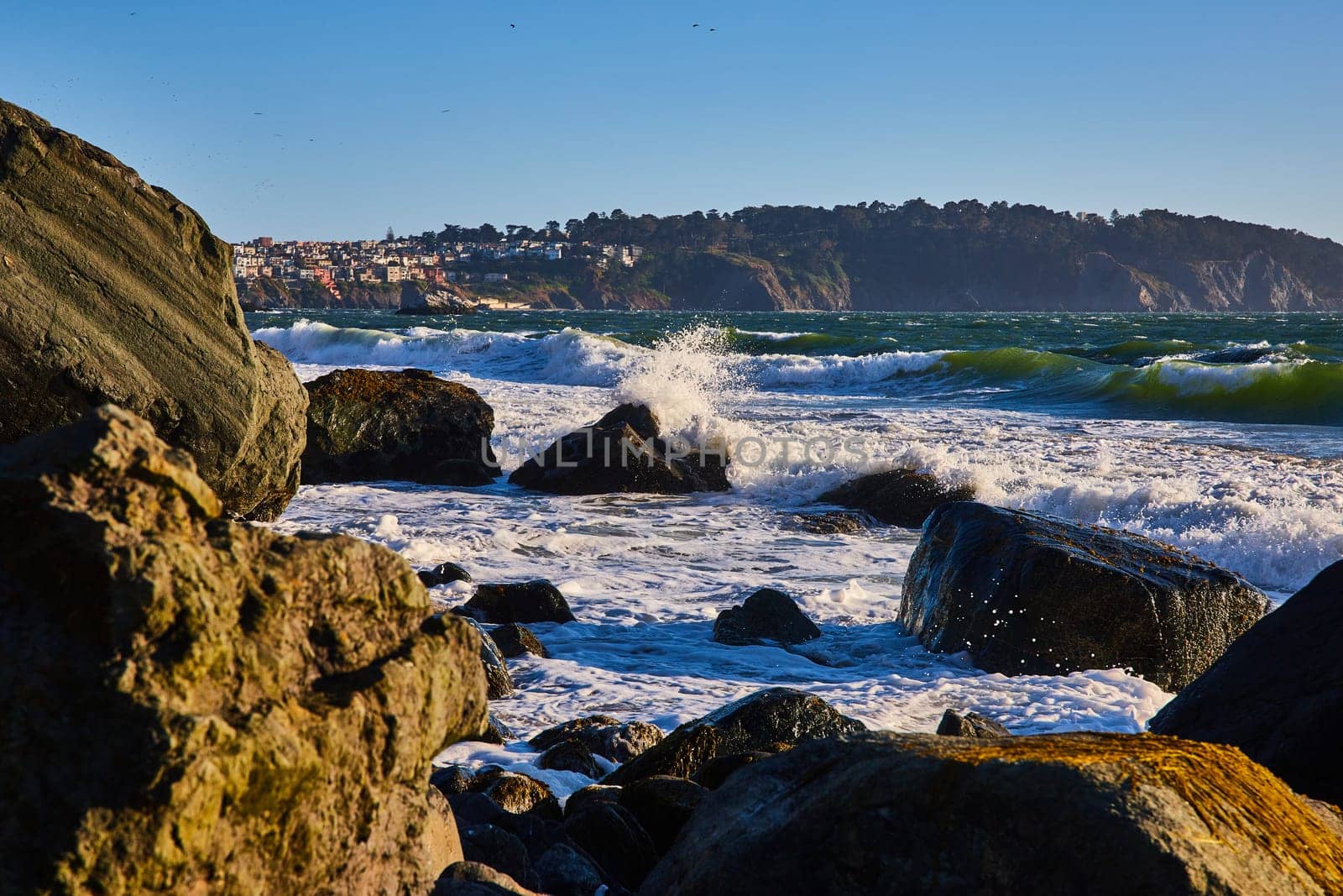 Image of Big waves rolling into massive boulders with ocean spray around partially submerged rock