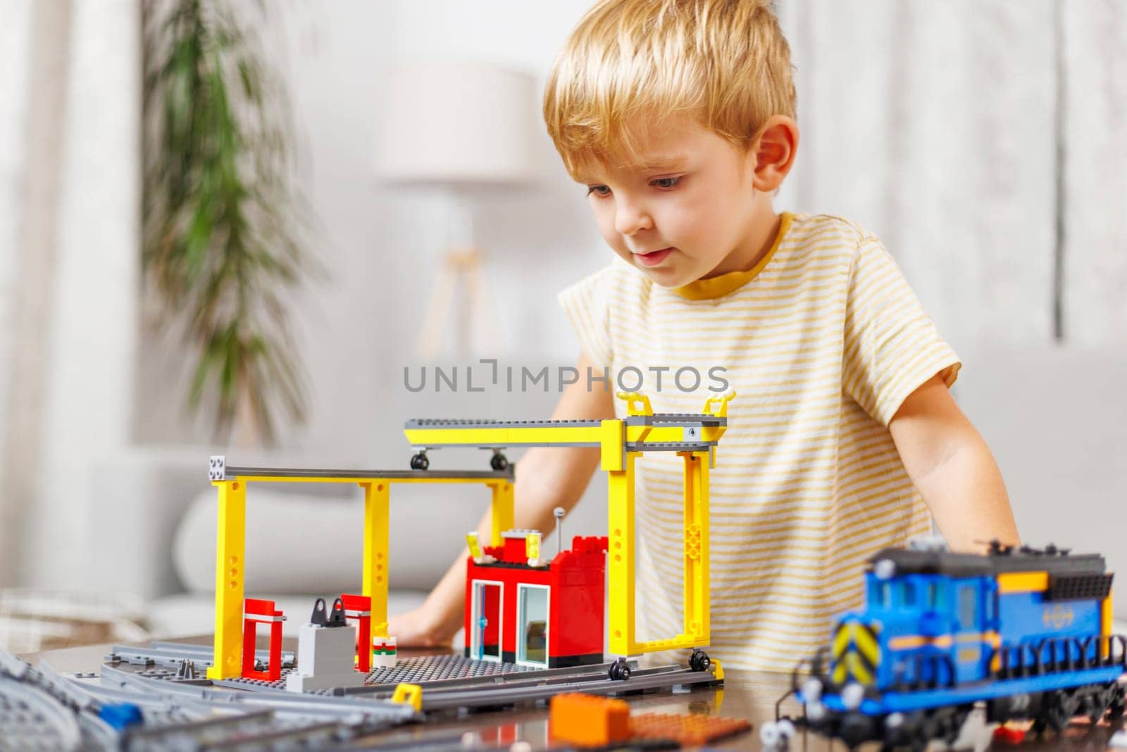 Child boy playing and building with colorful plastic bricks at the table. Early learning and development