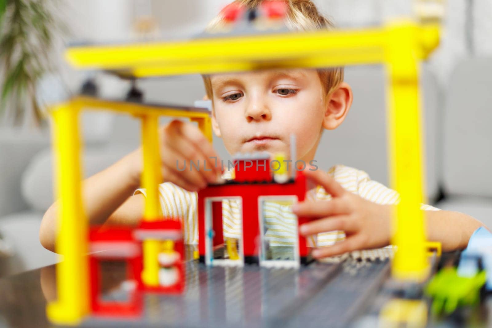 Child boy playing and building with colorful plastic bricks at the table. Early learning and development