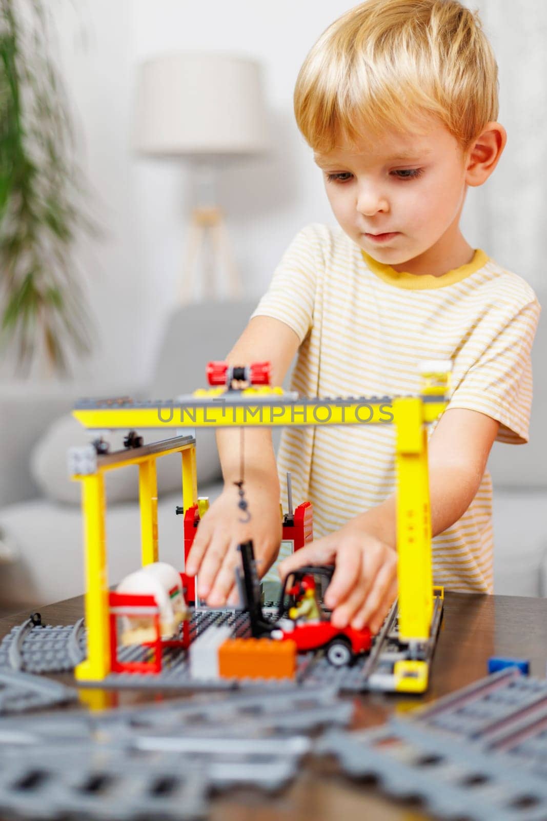 Child boy playing and building with colorful plastic bricks at the table by andreyz