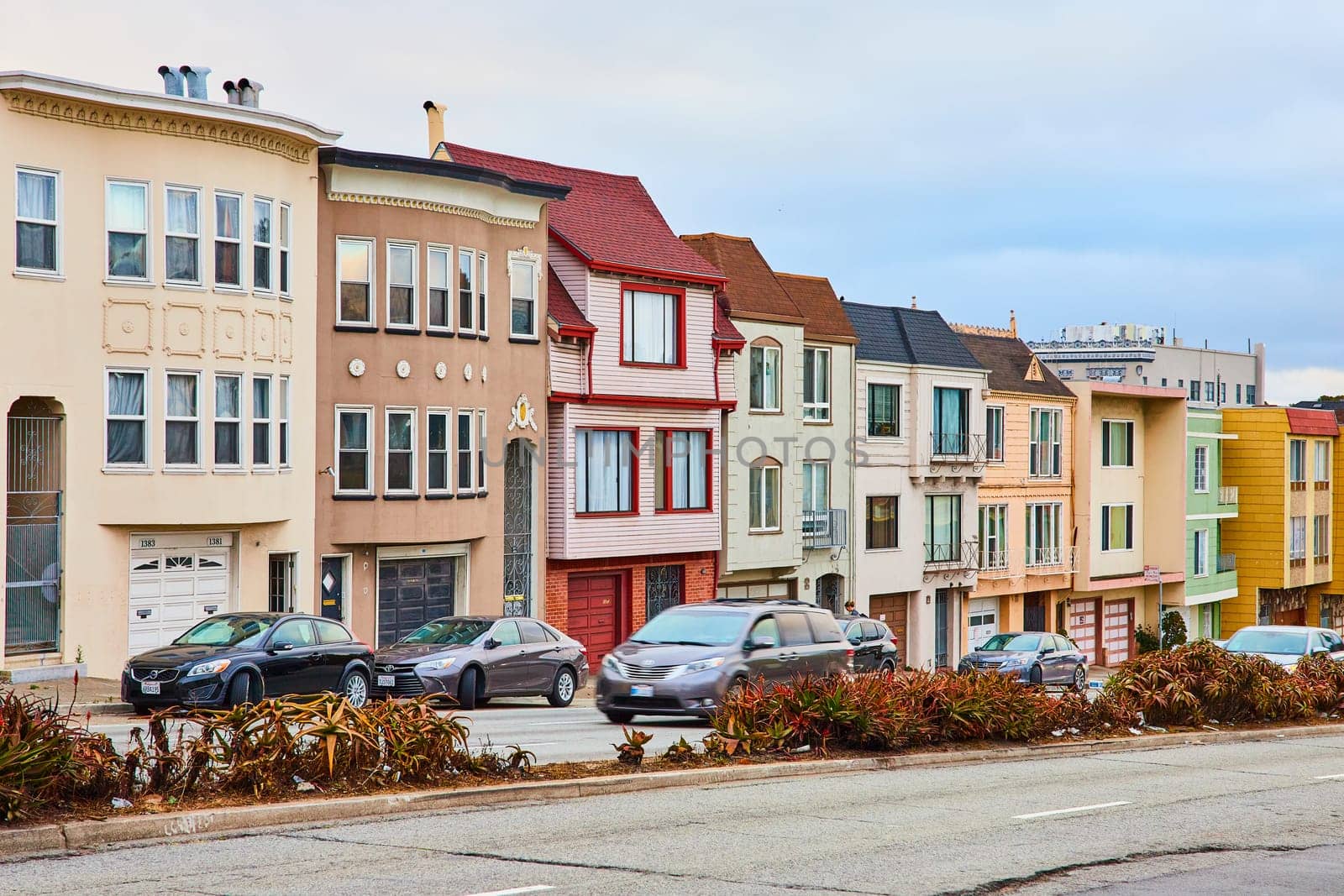 Image of Colorful row of San Francisco houses in compact housing with vehicles on street