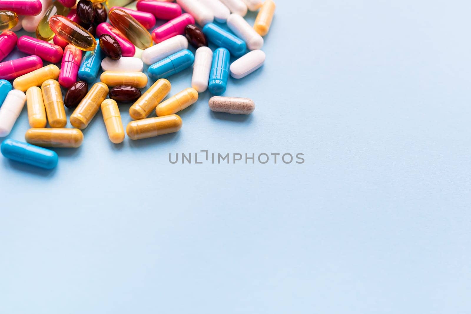 Lots of colorful pills and capsules for different symptoms on a blue background. Health and medicine concept. Place for an inscription