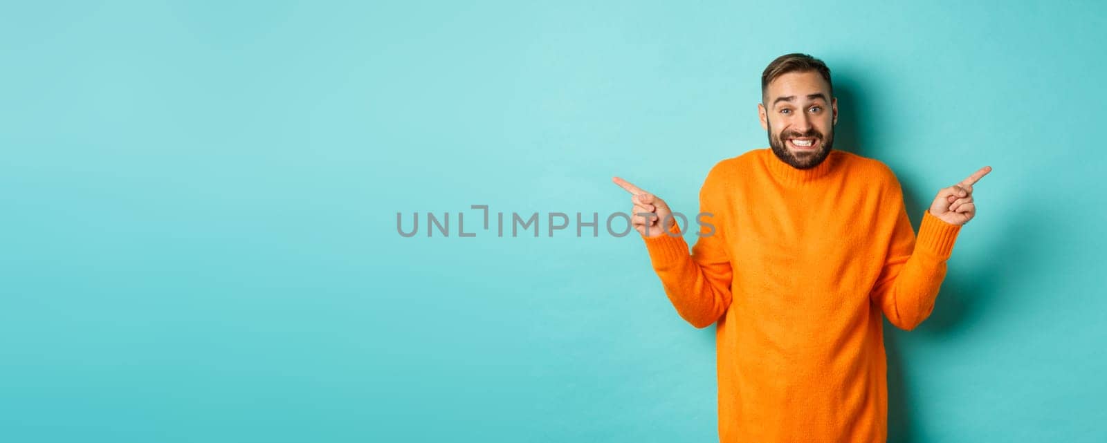 Confused handsome man shrugging indecisive, pointing fingers sideways, cant choose between two variants, standing against light blue background by Benzoix