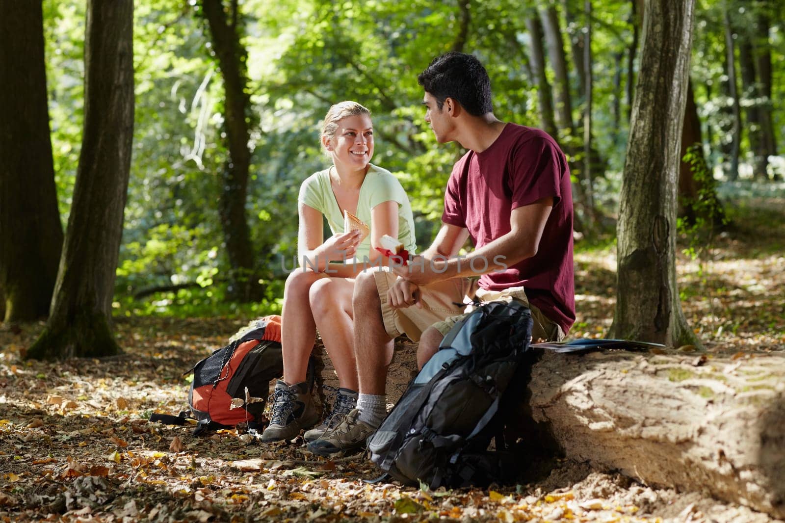young man and woman having lunch with sandwich during hiking excursion. Horizontal shape, full length