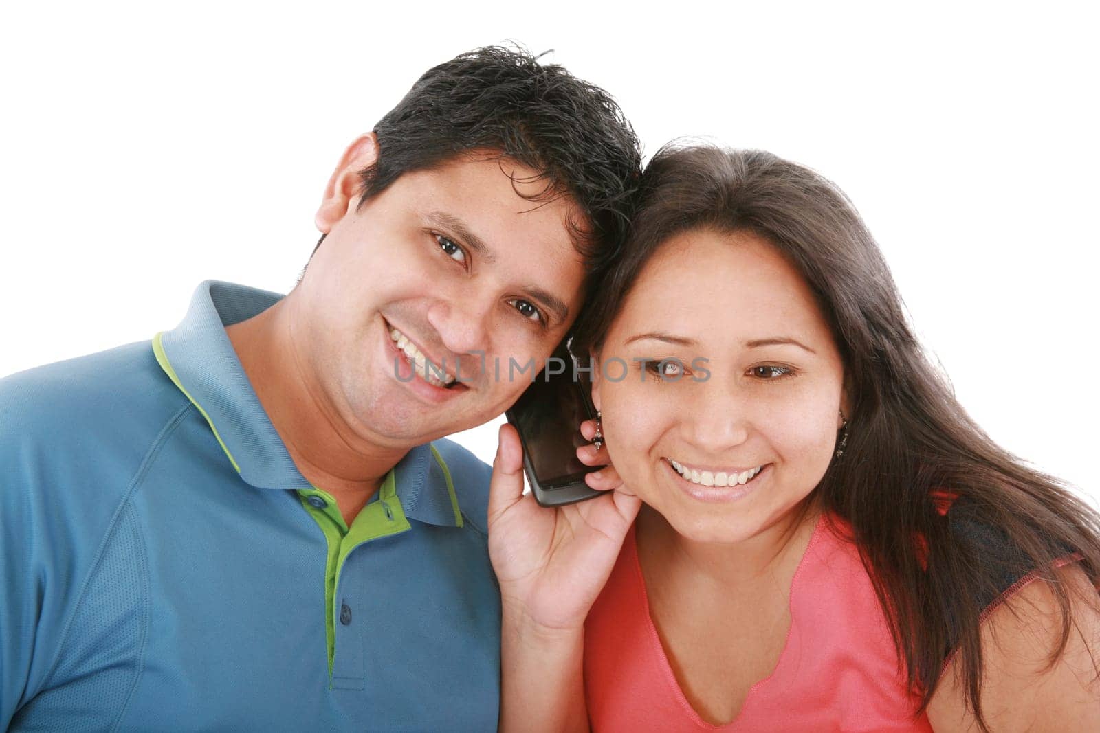 Couple are listening to a friend on a cell phone.