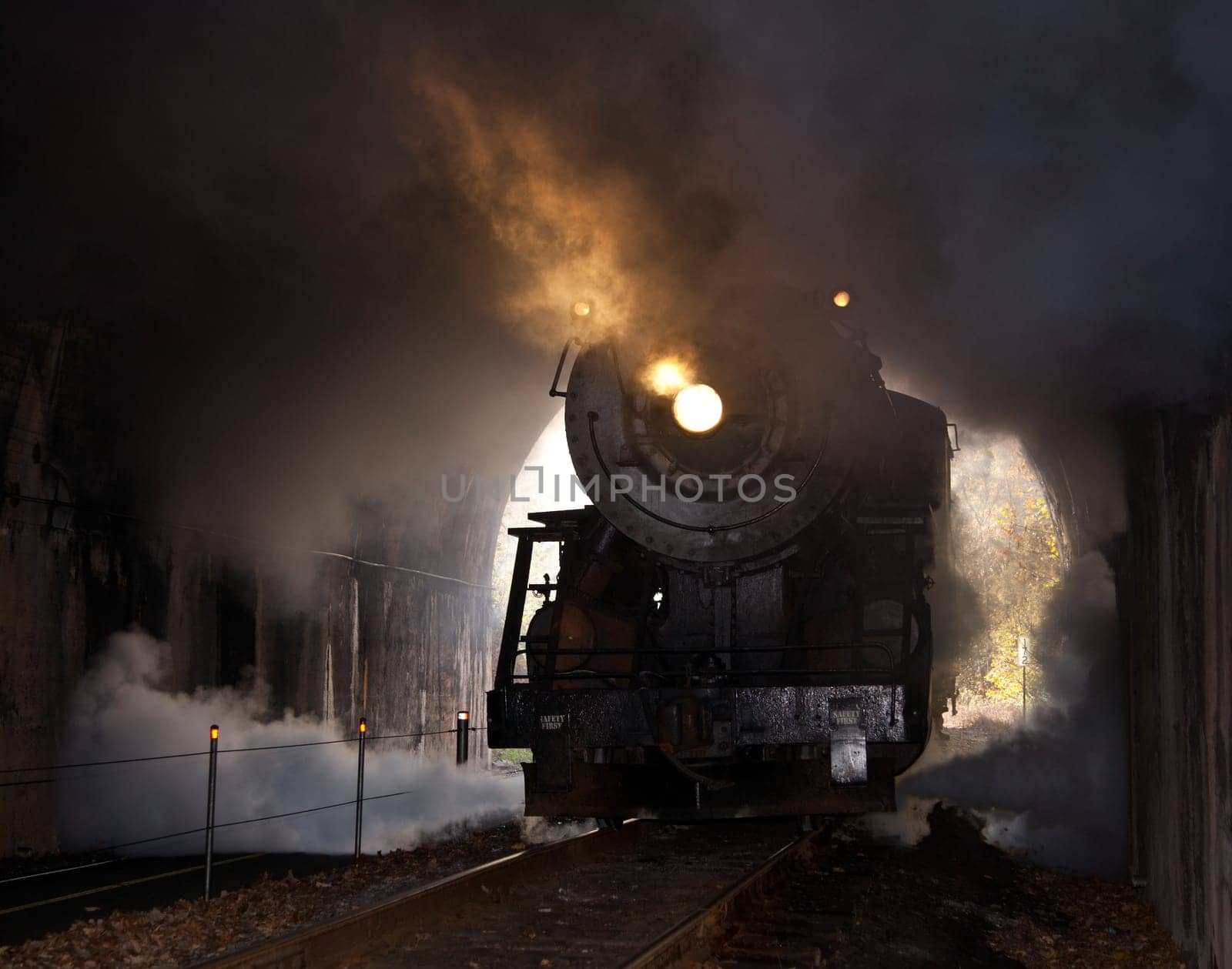 Old steam train pulling into a tunnel belching steam and smoke