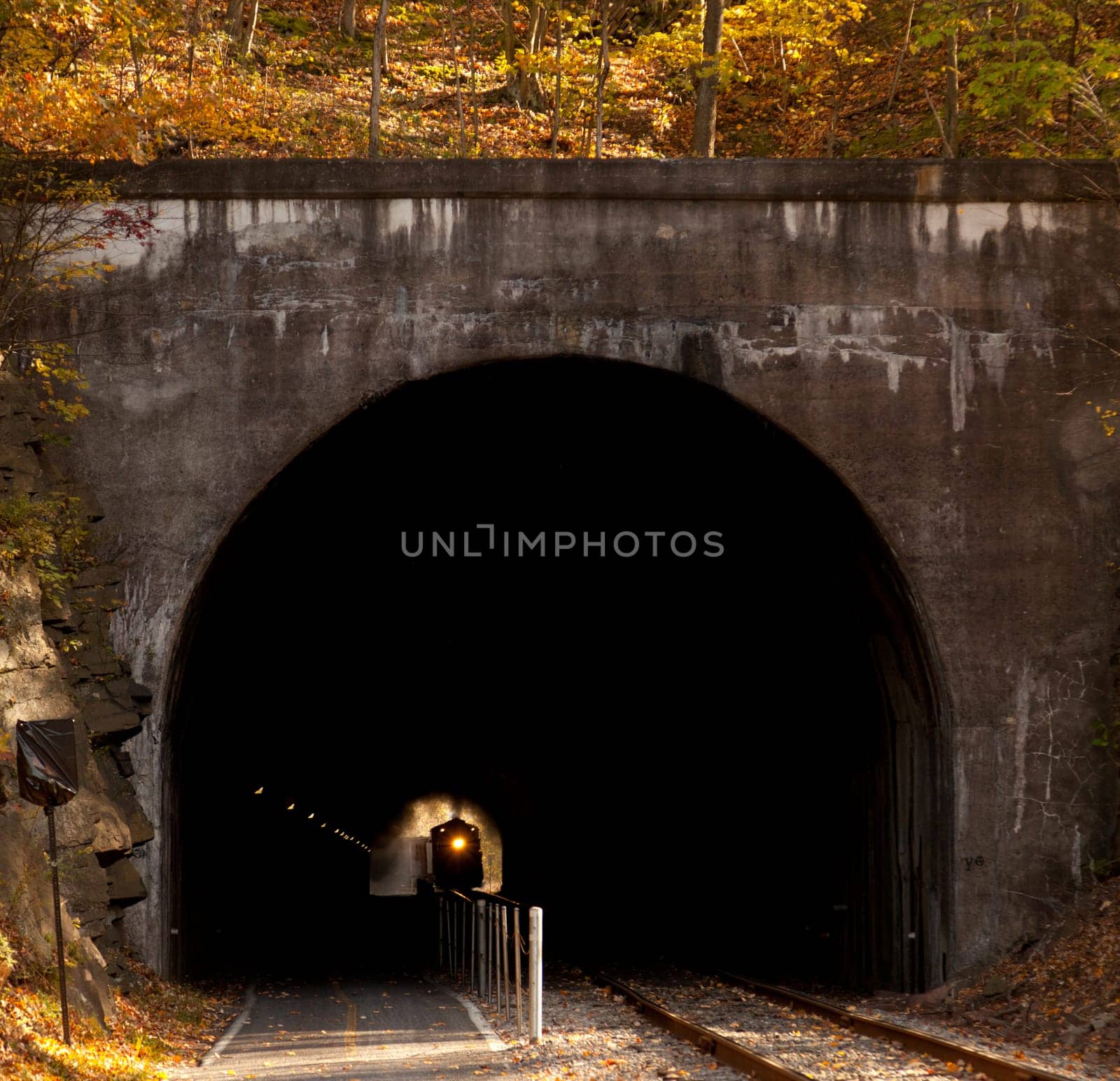 Old steam train pulling into a tunnel belching steam and smoke