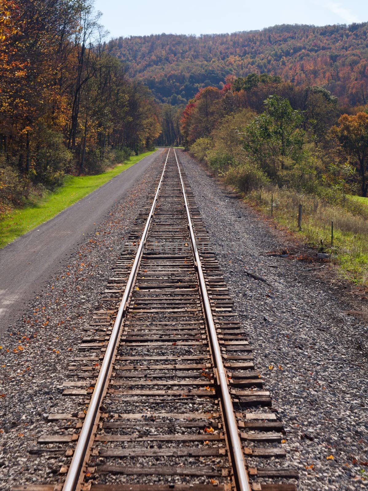 Cycling and hiking path besides railway lines in rural mountains in autumn