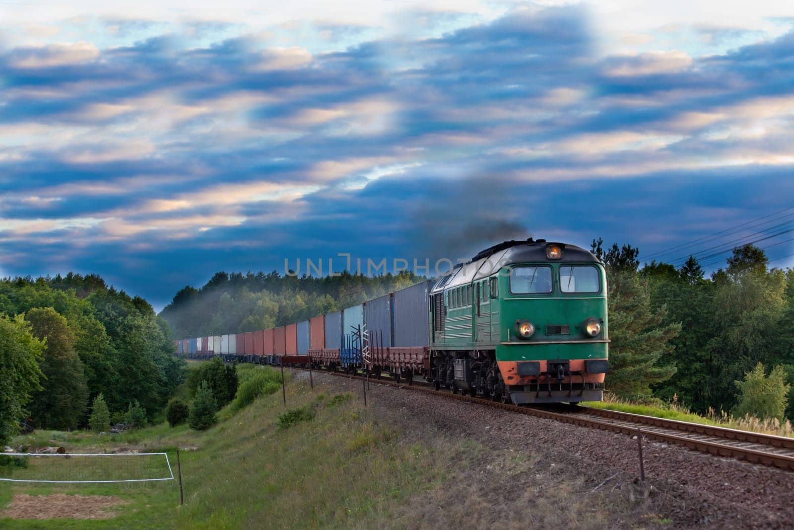 Freight train hauled by the diesel locomotive passing the forest
