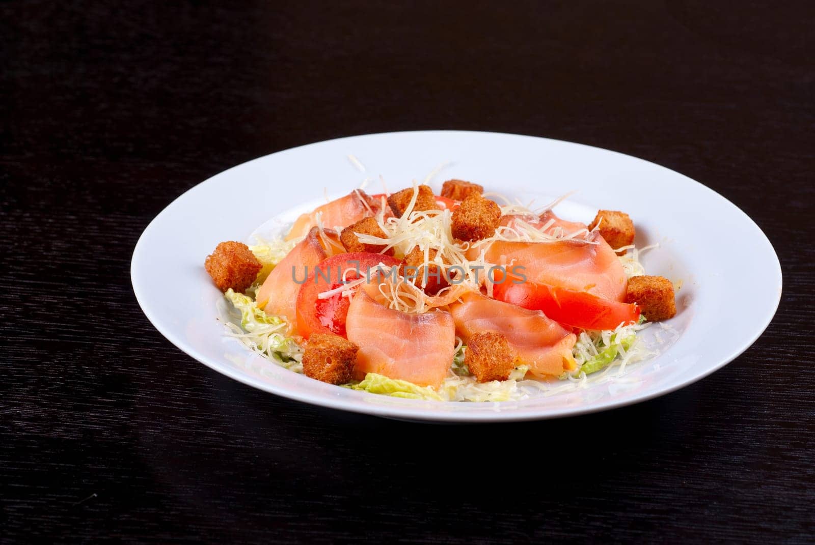 Salad of lettuce, chinese cabbage, tomato, garlic rusk, parmesan cheese, sauce and smoked salmon filet