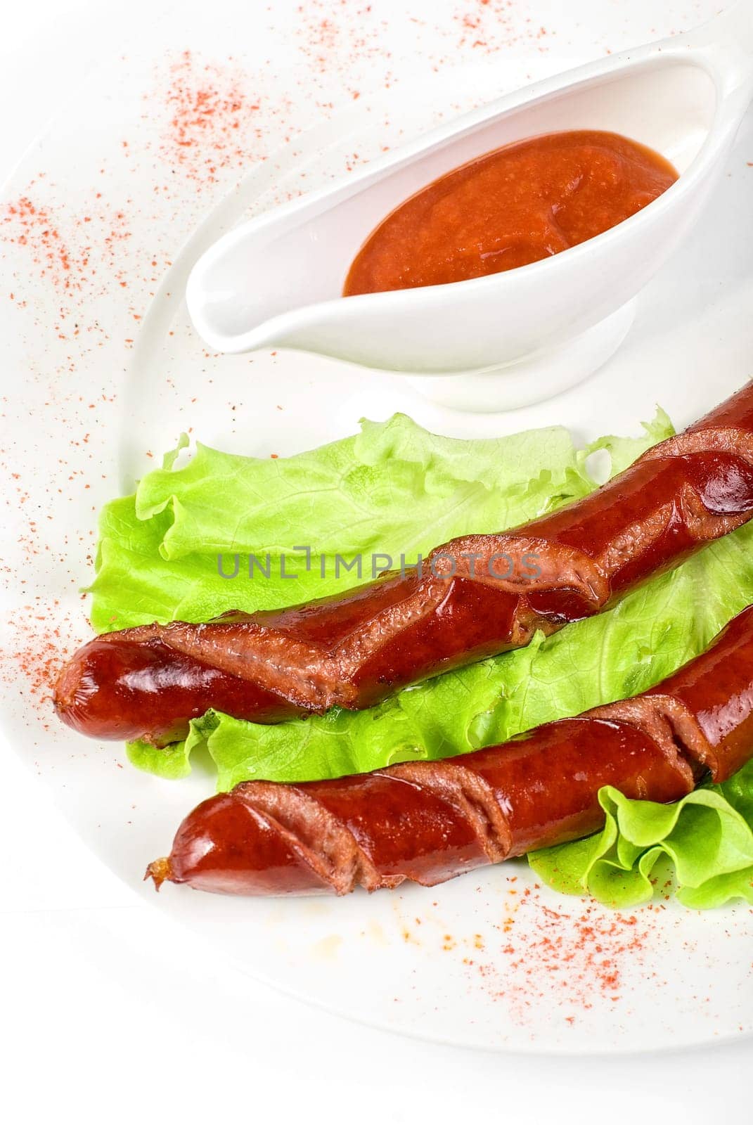 grilled sausage closeup with lettuce and sauce isolated on white