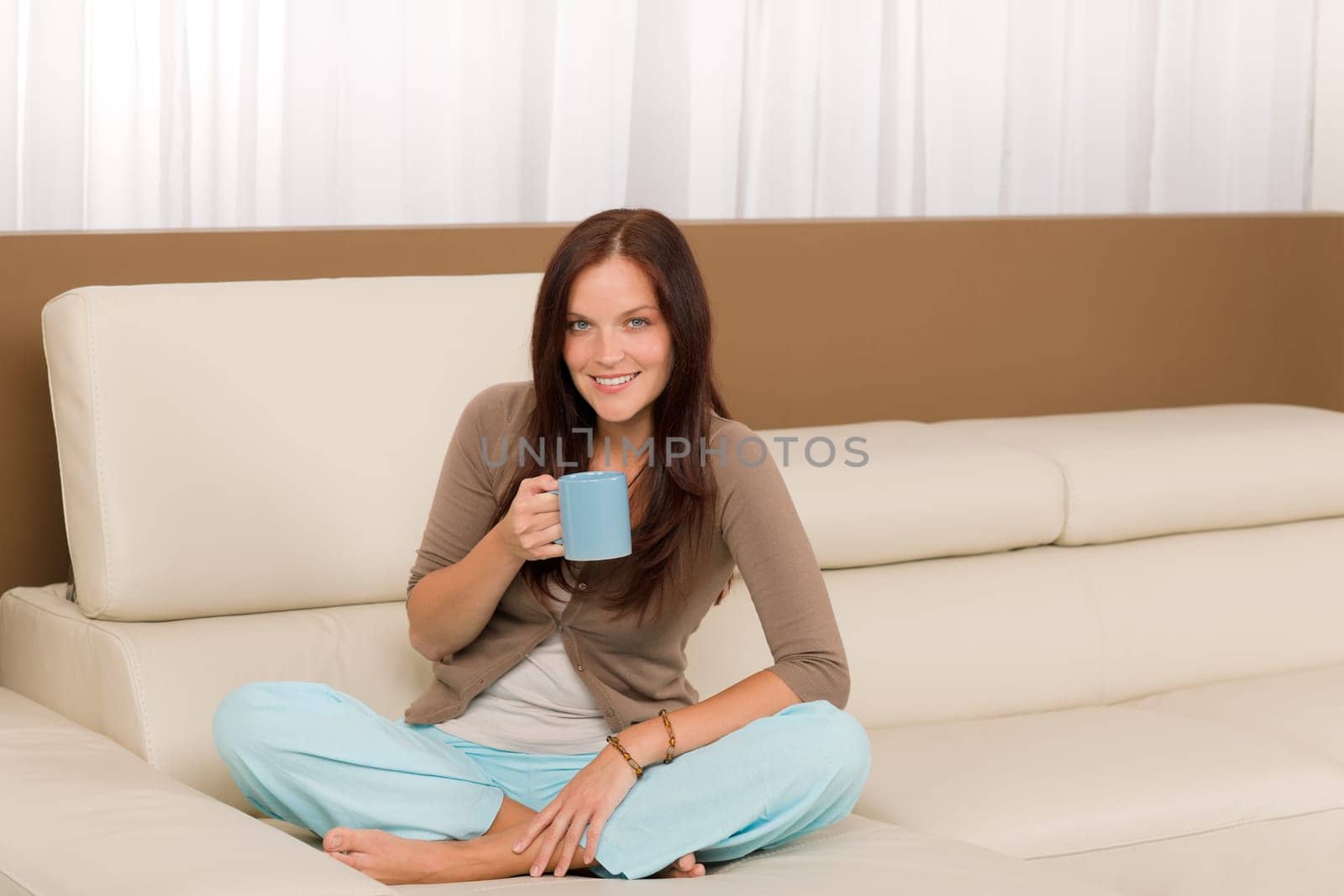 Attractive young woman at modern home sitting sofa drink coffee