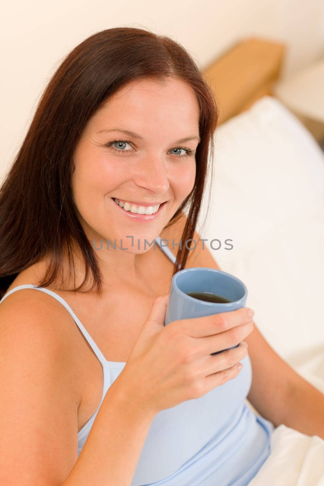 Bedroom - young woman drink coffee lying in white bed