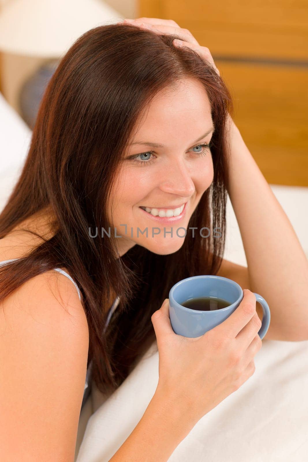 Bedroom - young woman drink coffee lying in white bed