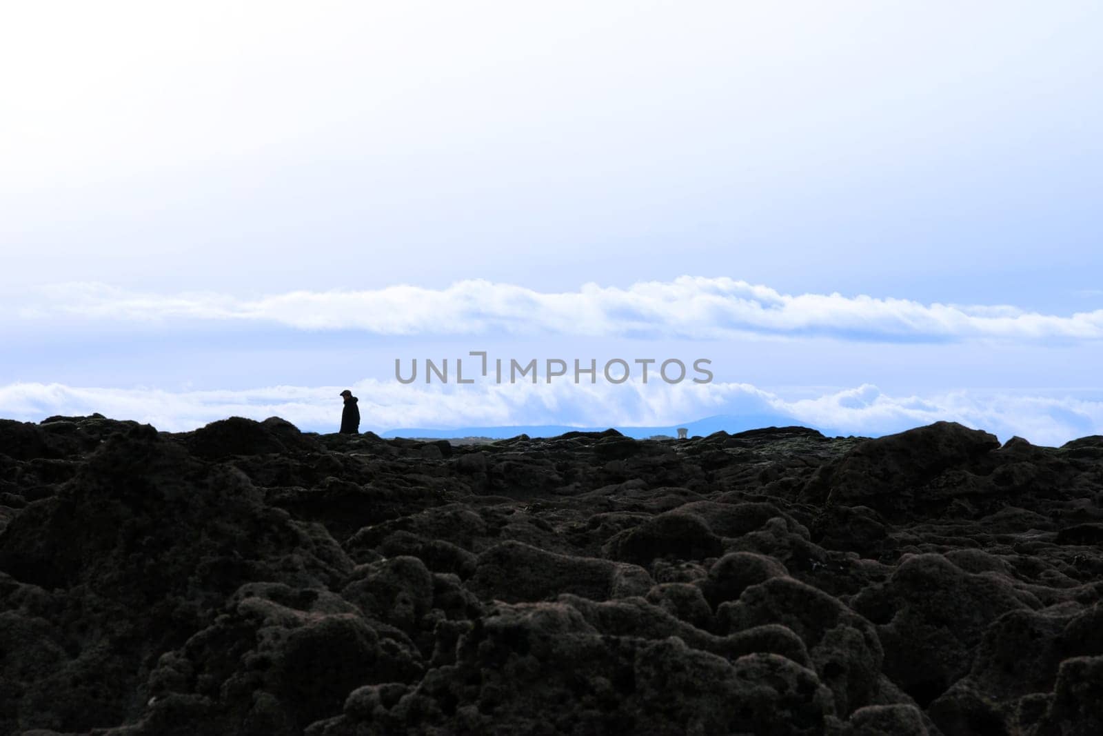 lone man walking among rocks with sun beaming down on the ballybunion coastline on irelands west coast