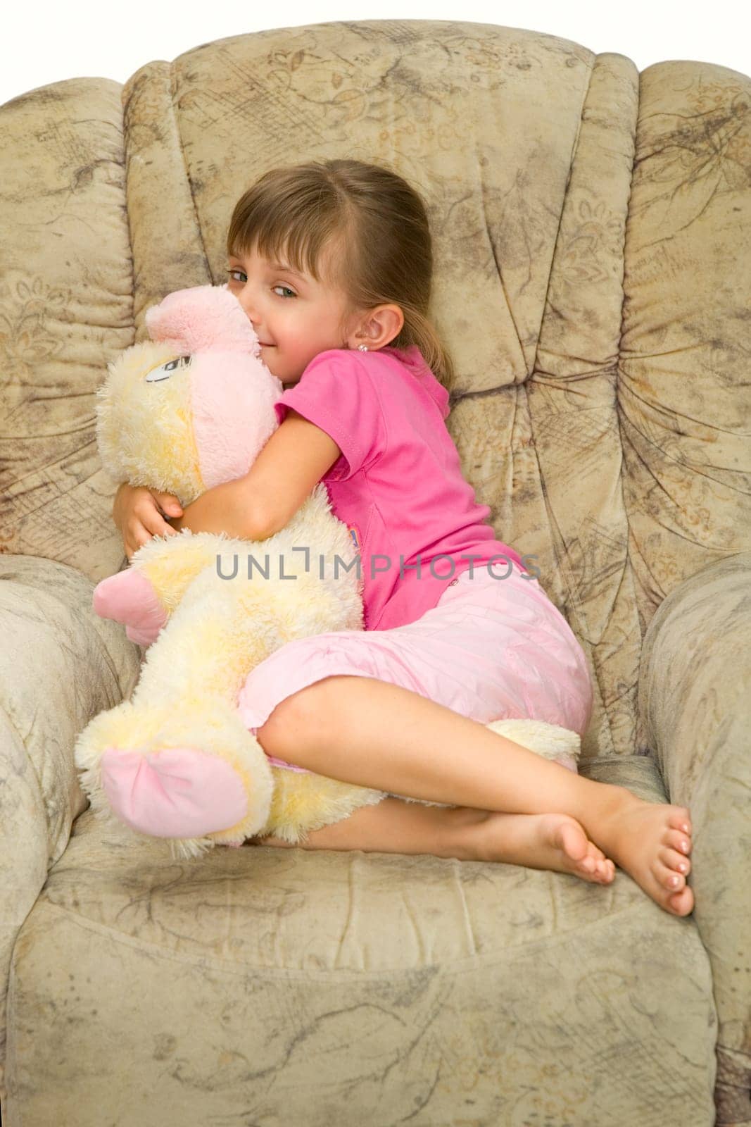 The girl lays in an armchair on the big soft toy