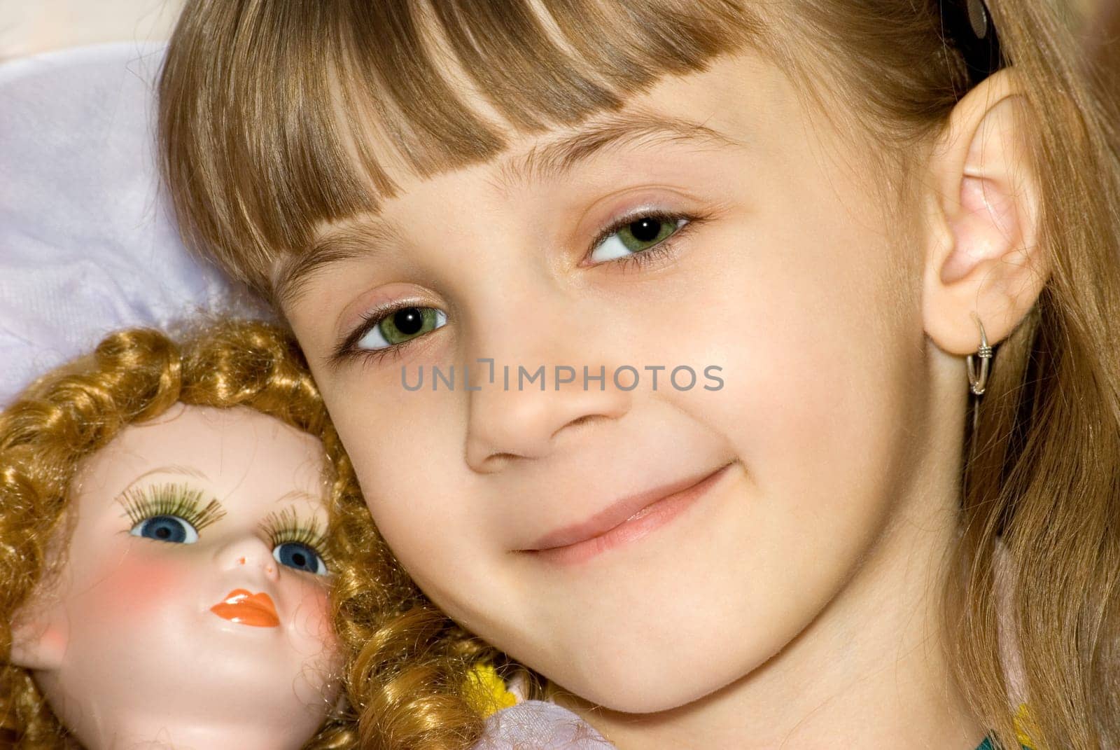 The girl has nestled on a doll and smiles