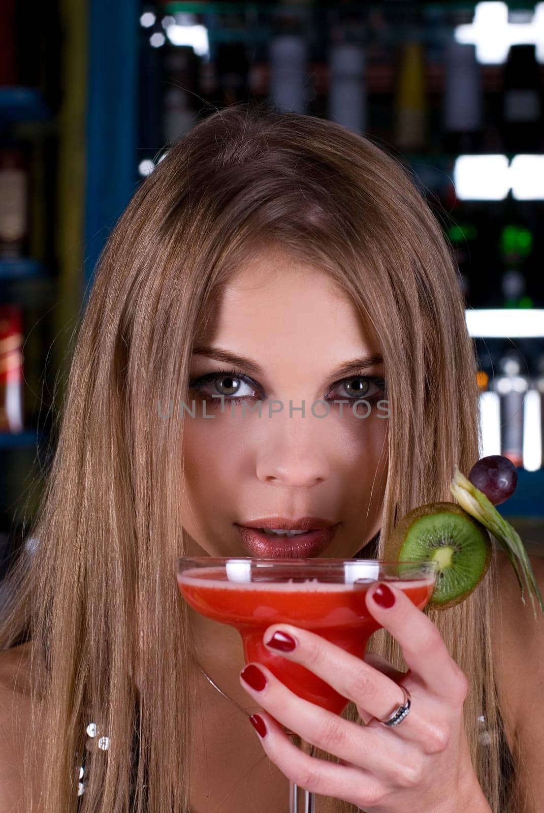Beauty young woman portrait with a glass drinking a cocktail at a bar