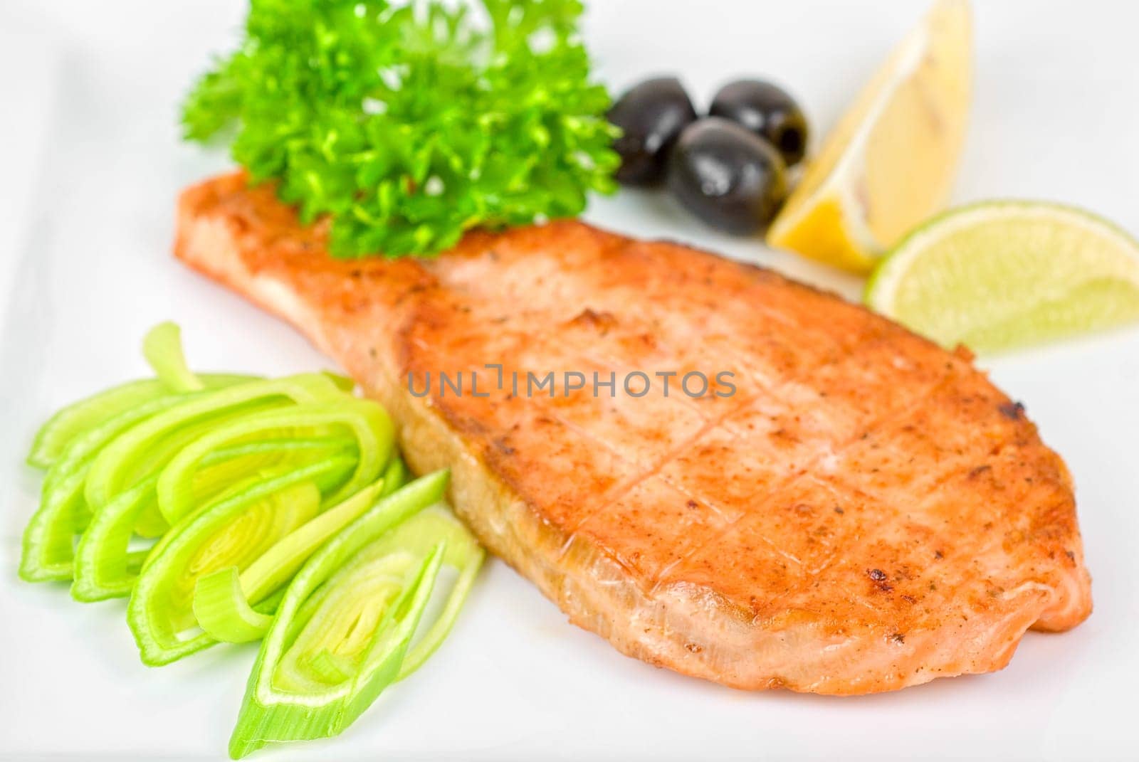 Grilled salmon steak with greens,onion, lemon, lime and olive
