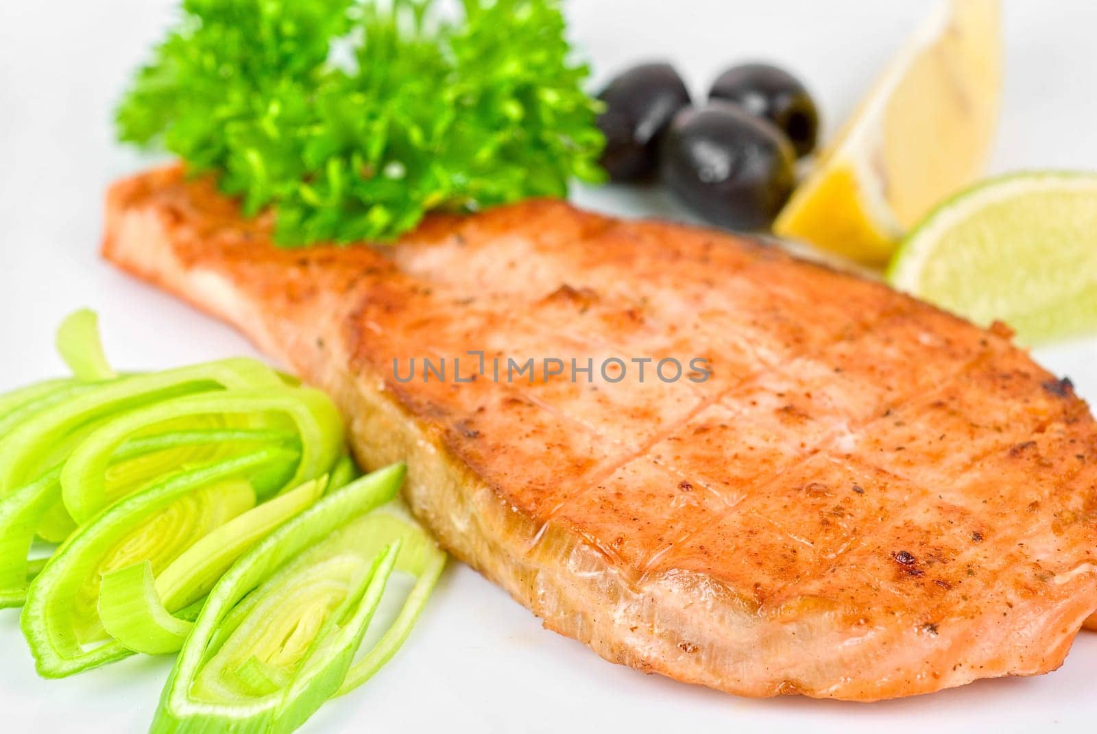 Grilled salmon steak with greens,onion, lemon, lime and olive