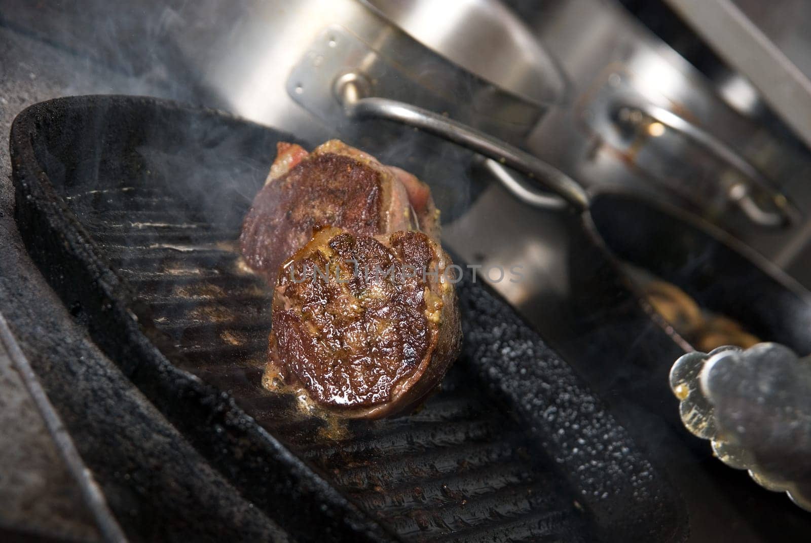 Tasty beef steak grilling in a cast-iron ribbed fry pan