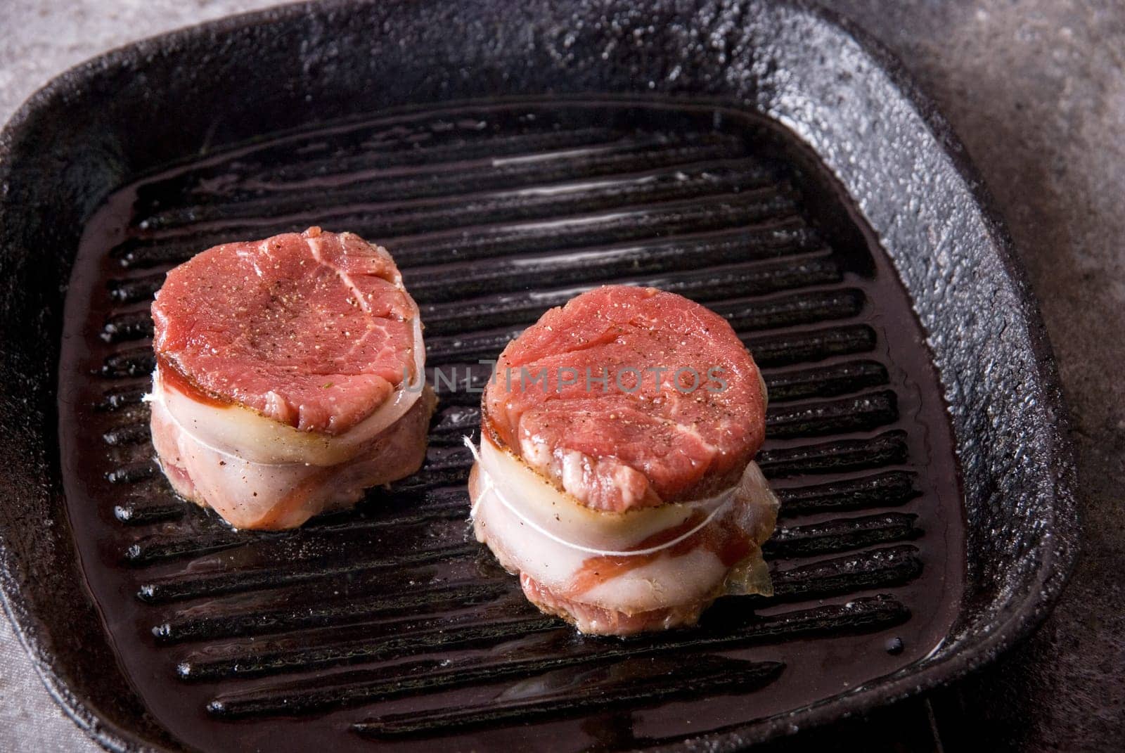Tasty beef steak grilling in a cast-iron ribbed fry pan