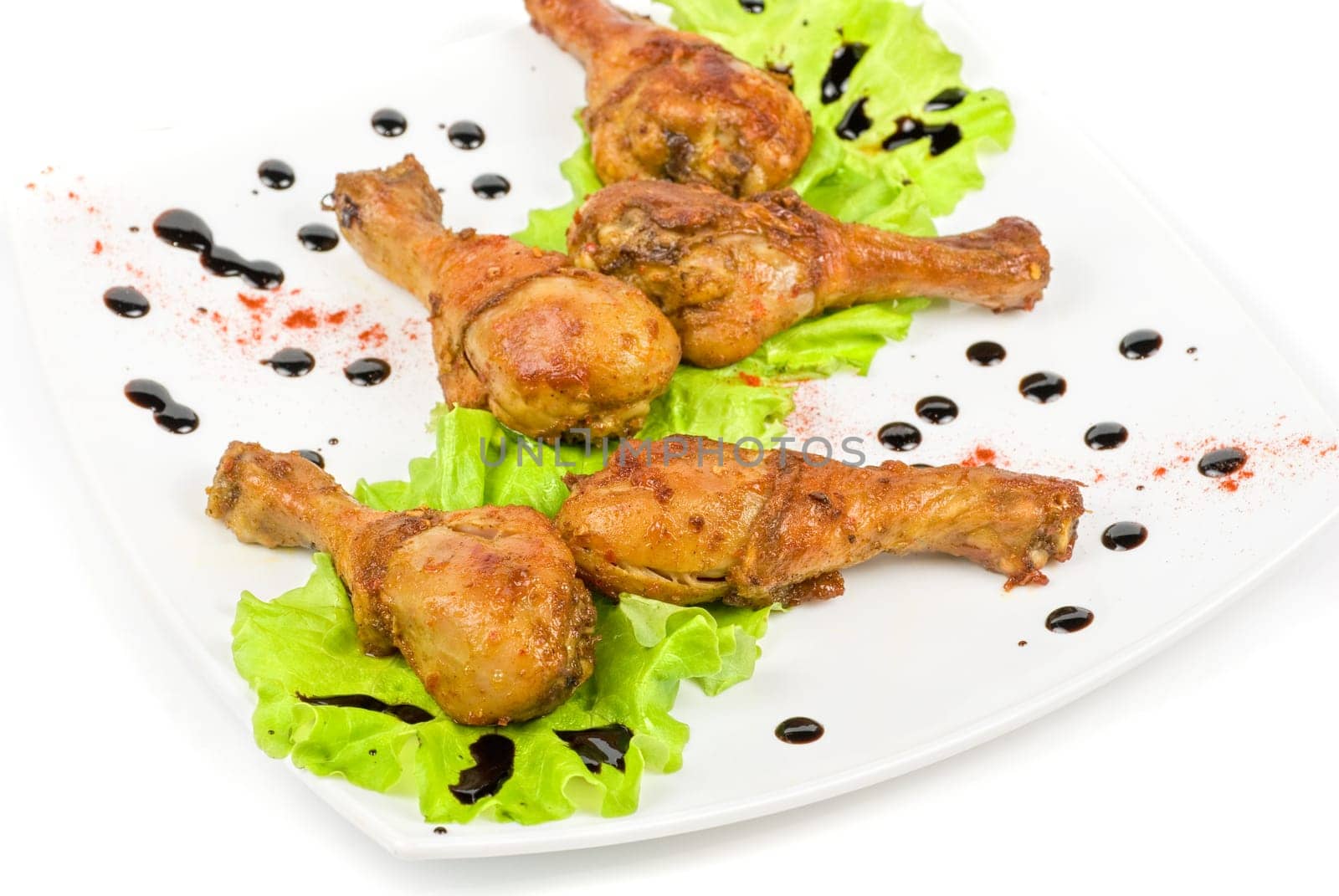 chicken drumstick closeup at white plate with lettuce