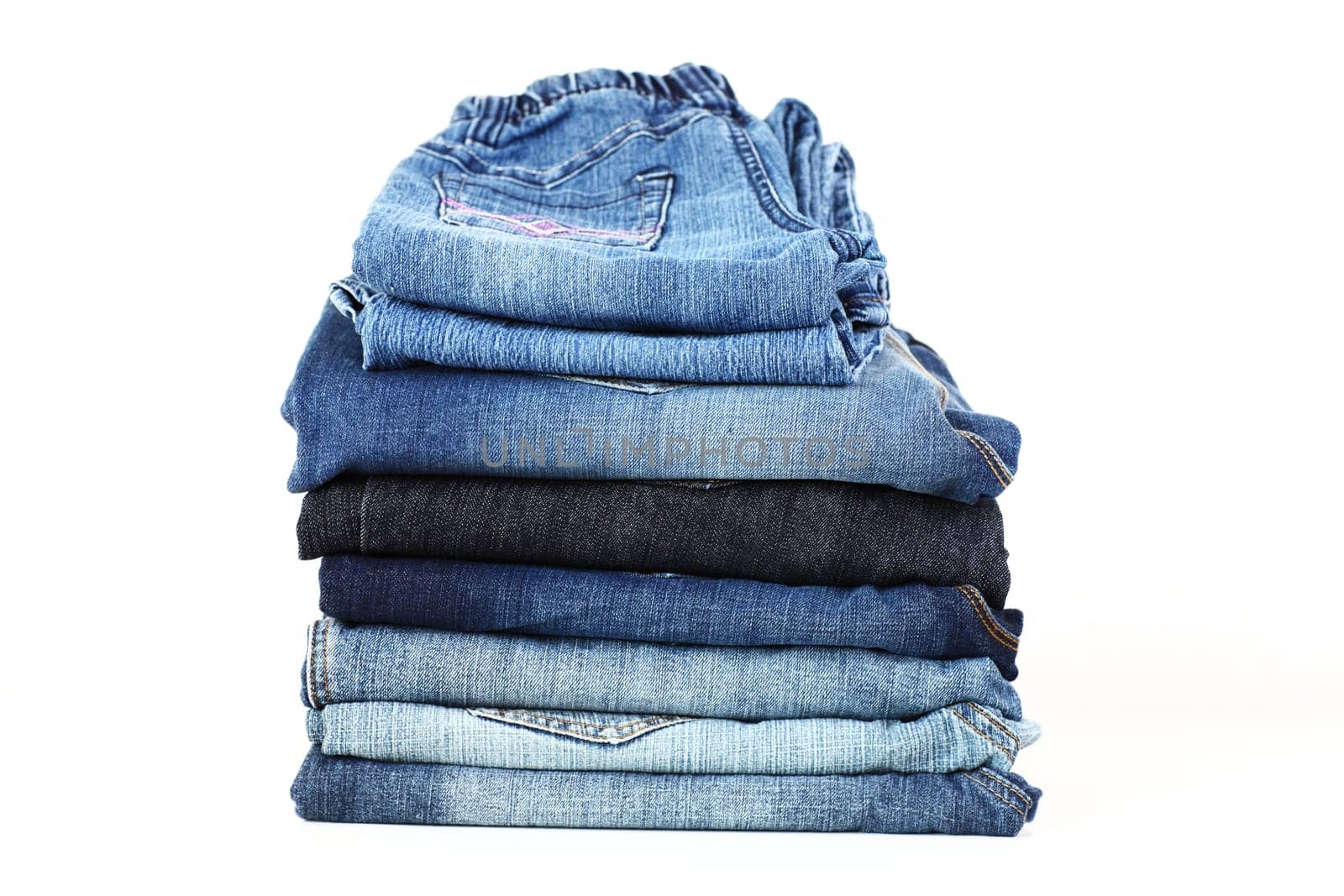 Stack of different jeans on white background