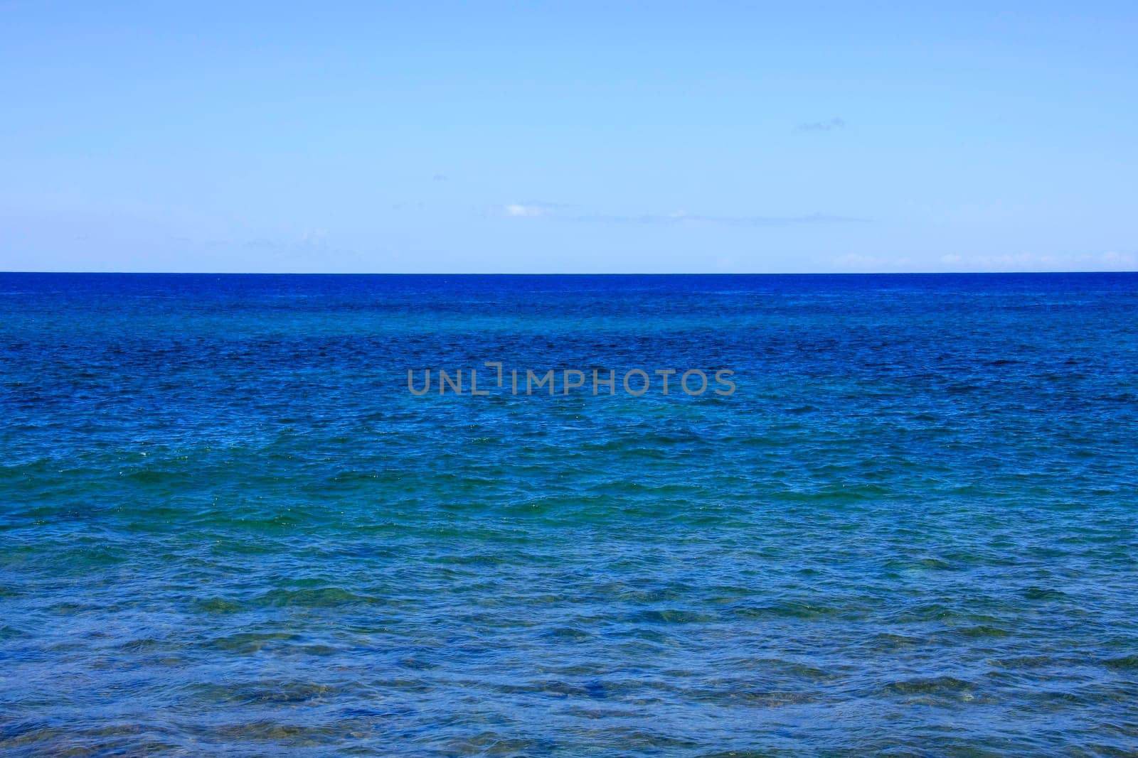 Blue sea with barely cloudy sky