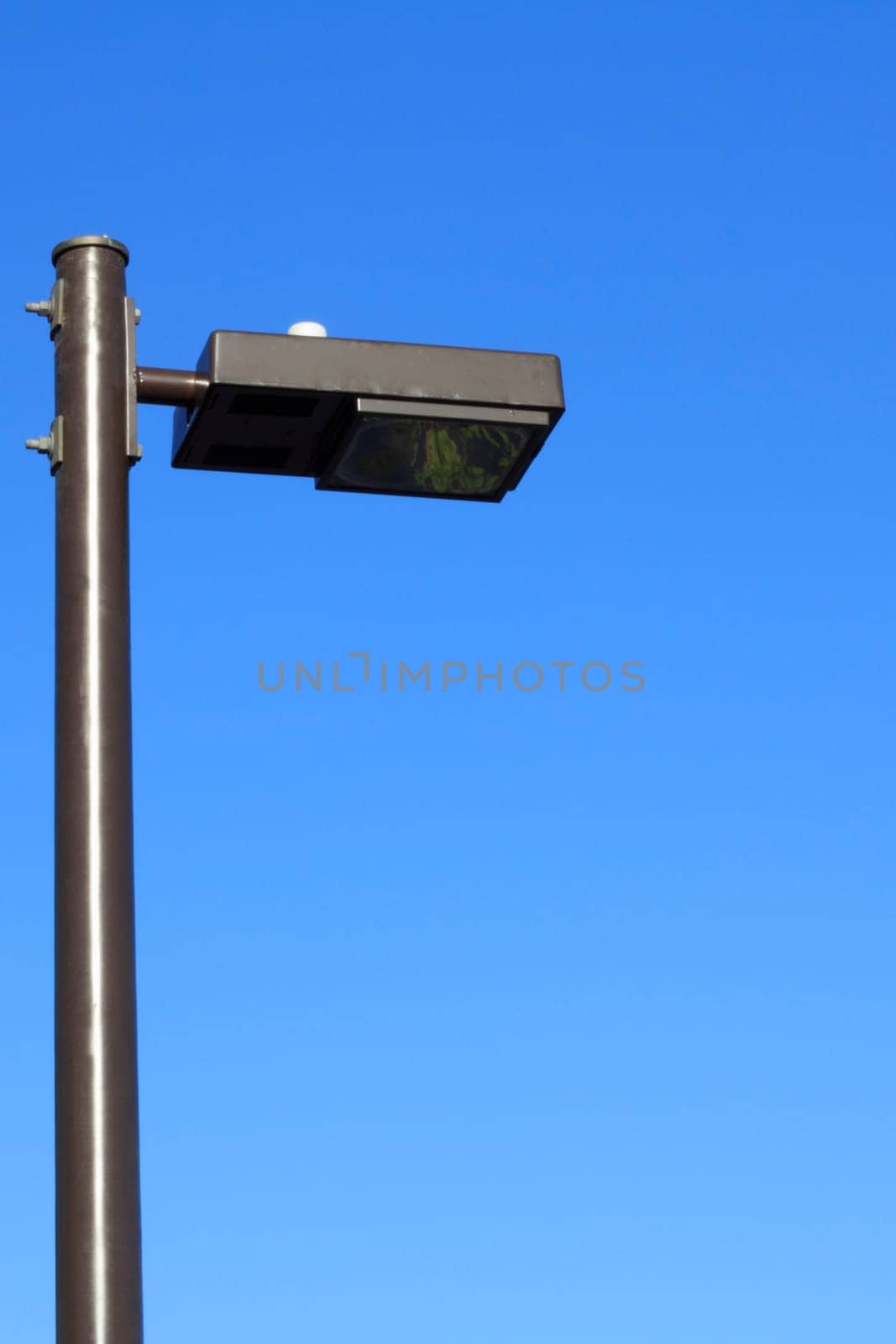 Public street light tall in a morning bright blue sky.