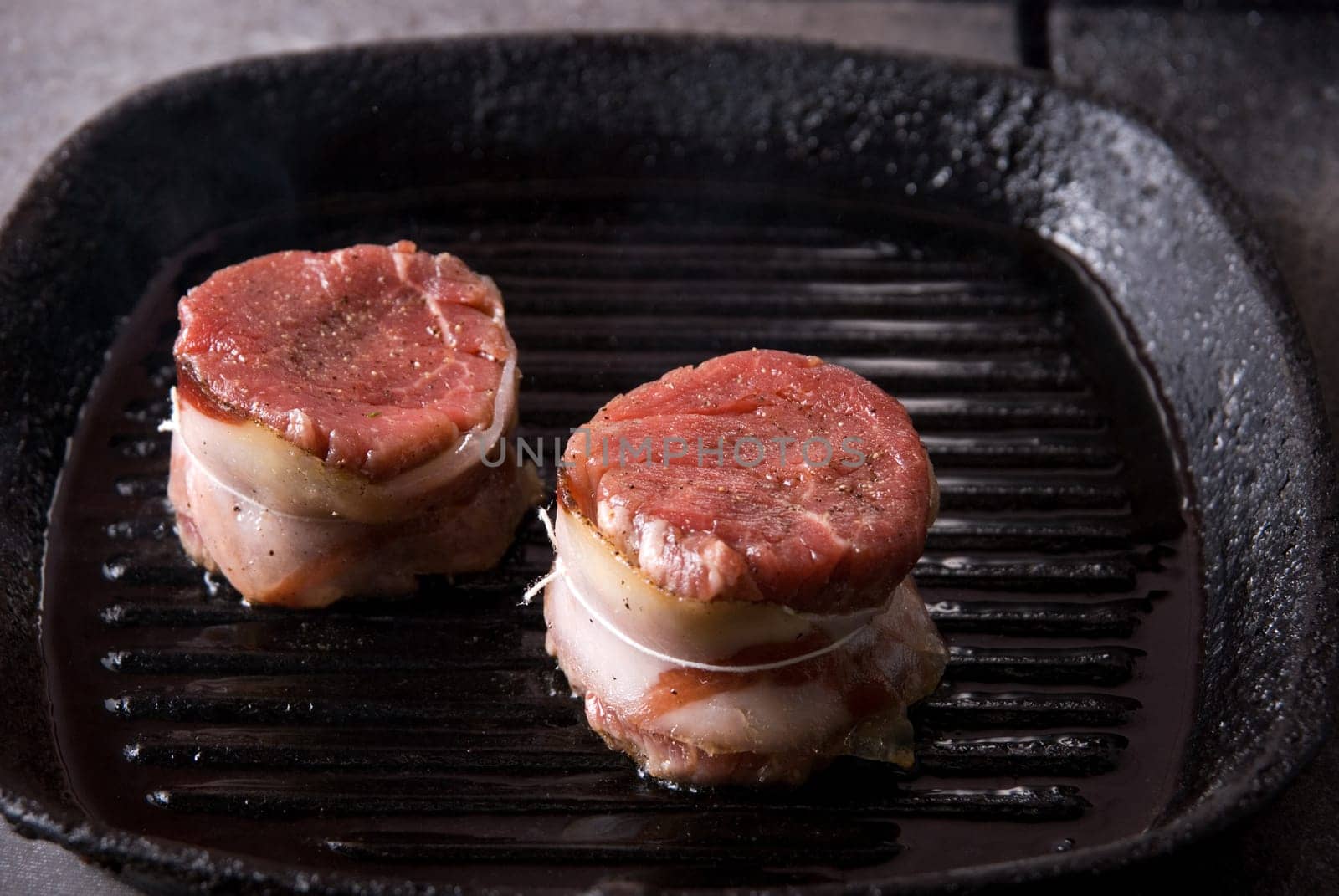 Tasty beef steak grilling in a cast-iron ribbed fry pan