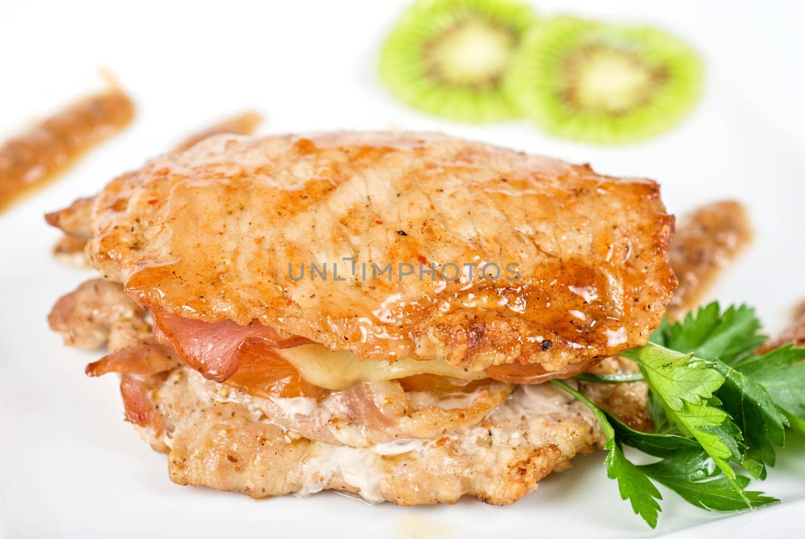 Cooked pork chop with kiwi and parsley on a white