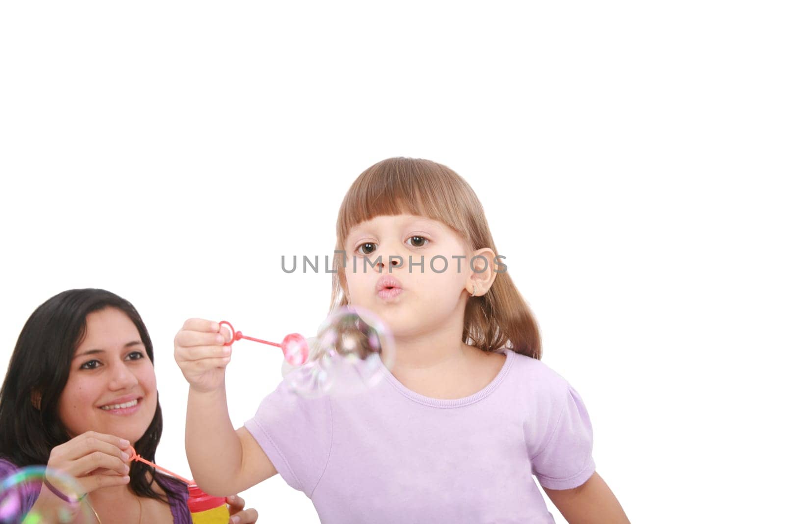 Portrait of funny lovely little girl blowing soap bubbles with her mom. Little girl on focus.