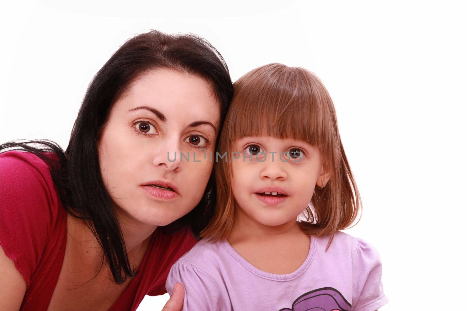 Mother and cute little daughter watch TV in great concentration