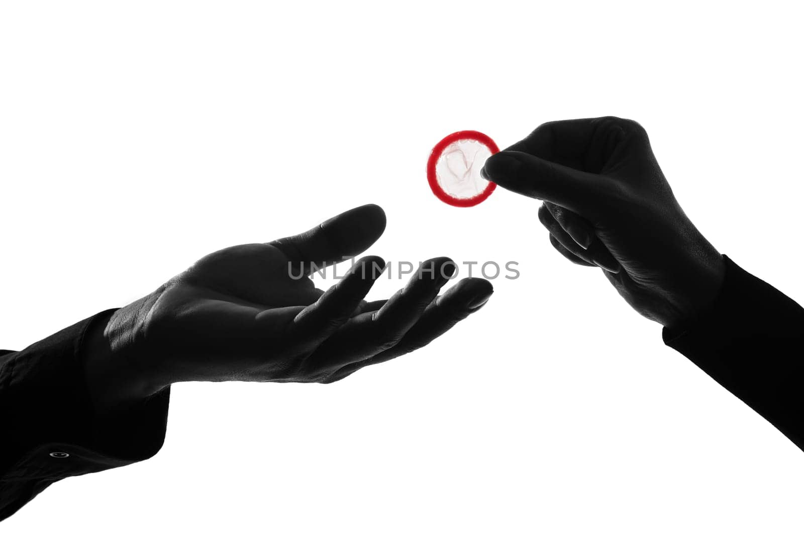 one caucasian couple man and woman hands holding tossing offering giving condom  in studio silhouette isolated on white background