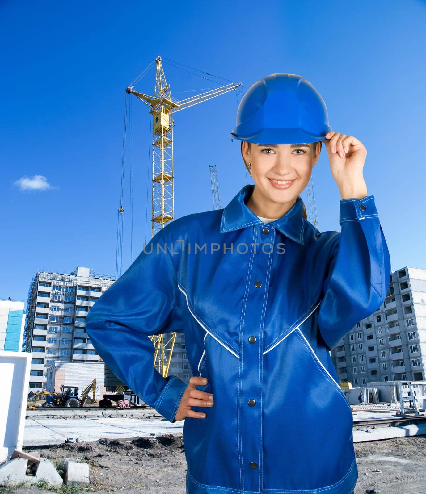 Builder pretty girl at helmet on a building background