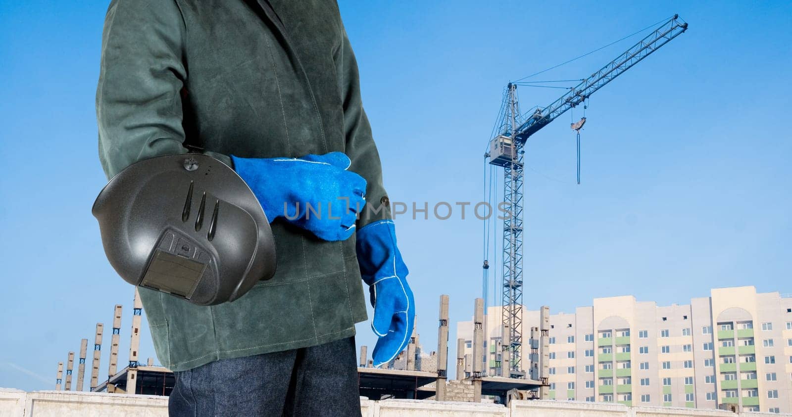 male welder closeup with welding equipment on building background