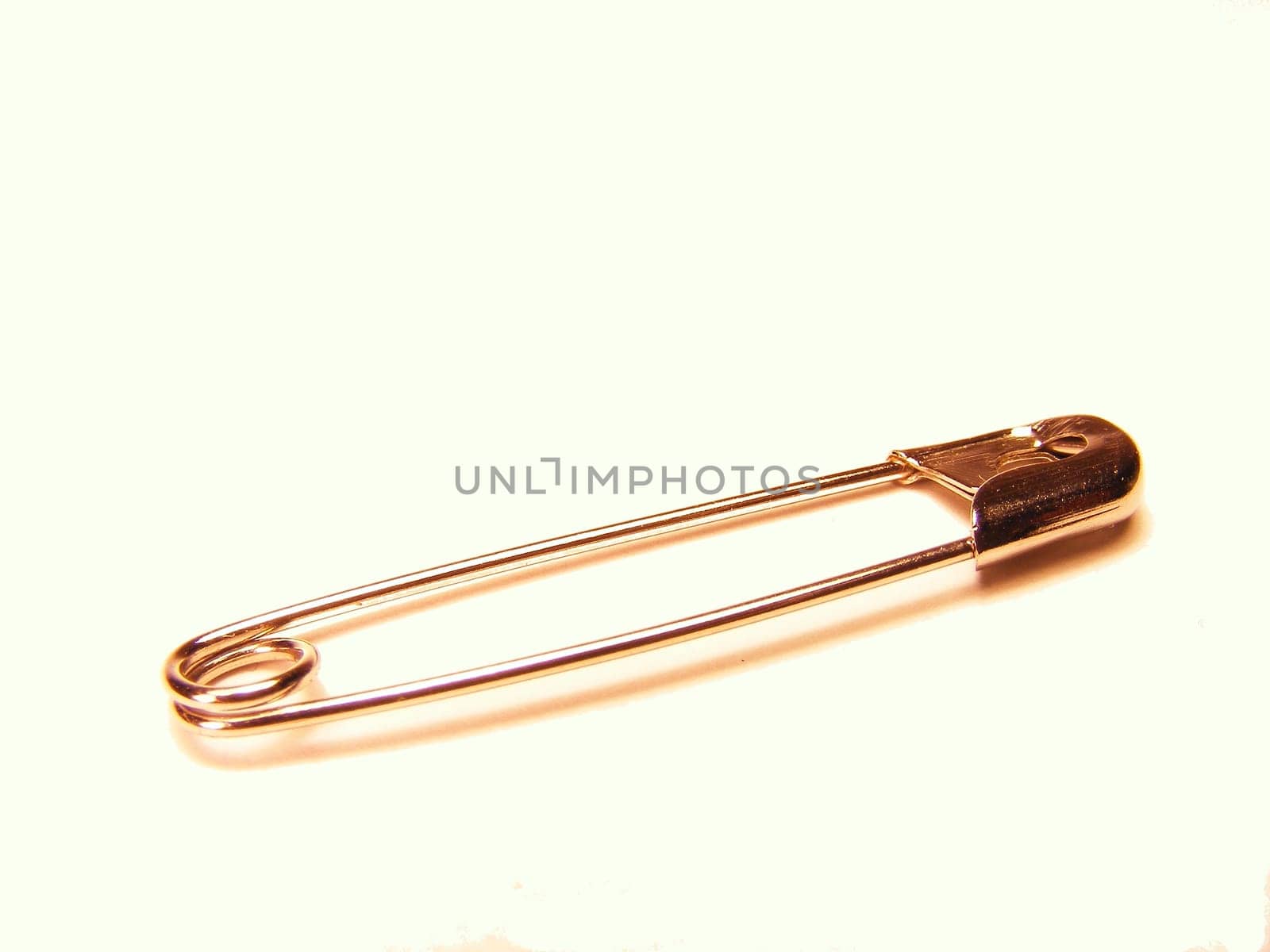 A silver safety pin on a white background